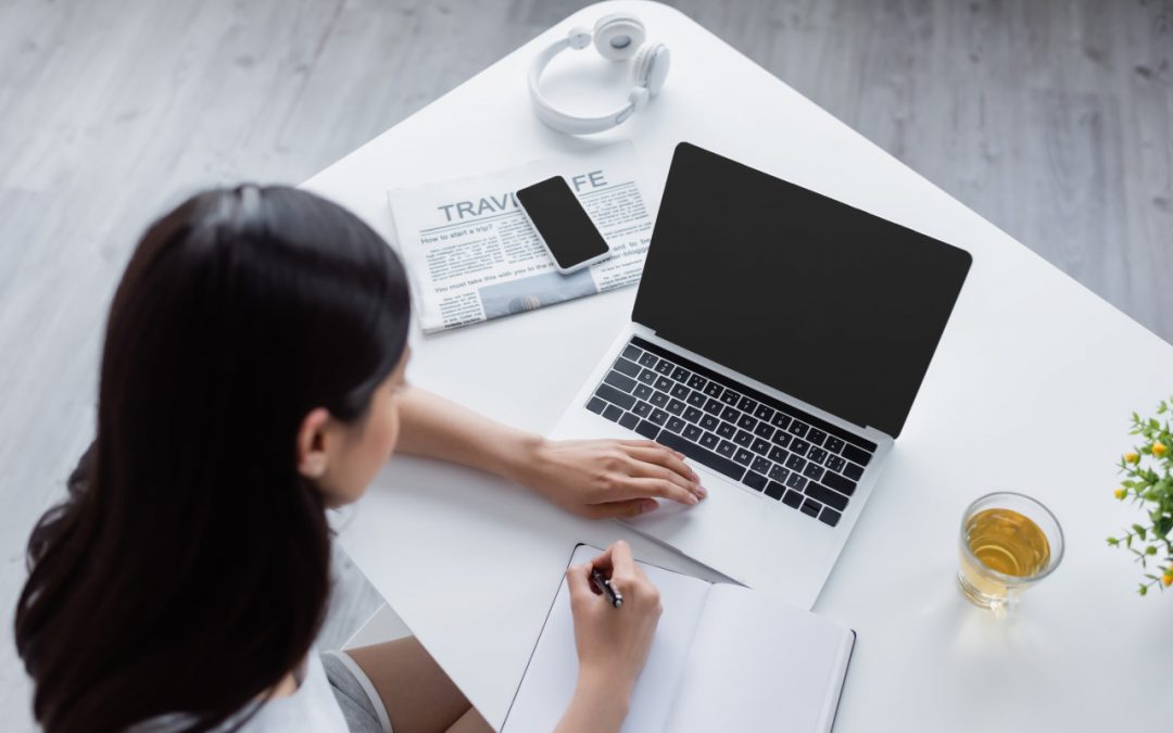 Kobieta szuka informacji, przed nią stoi laptop, obok niego leży gazeta